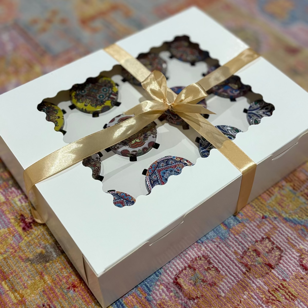 Decorative items in a box with a gold ribbon on a patterned surface