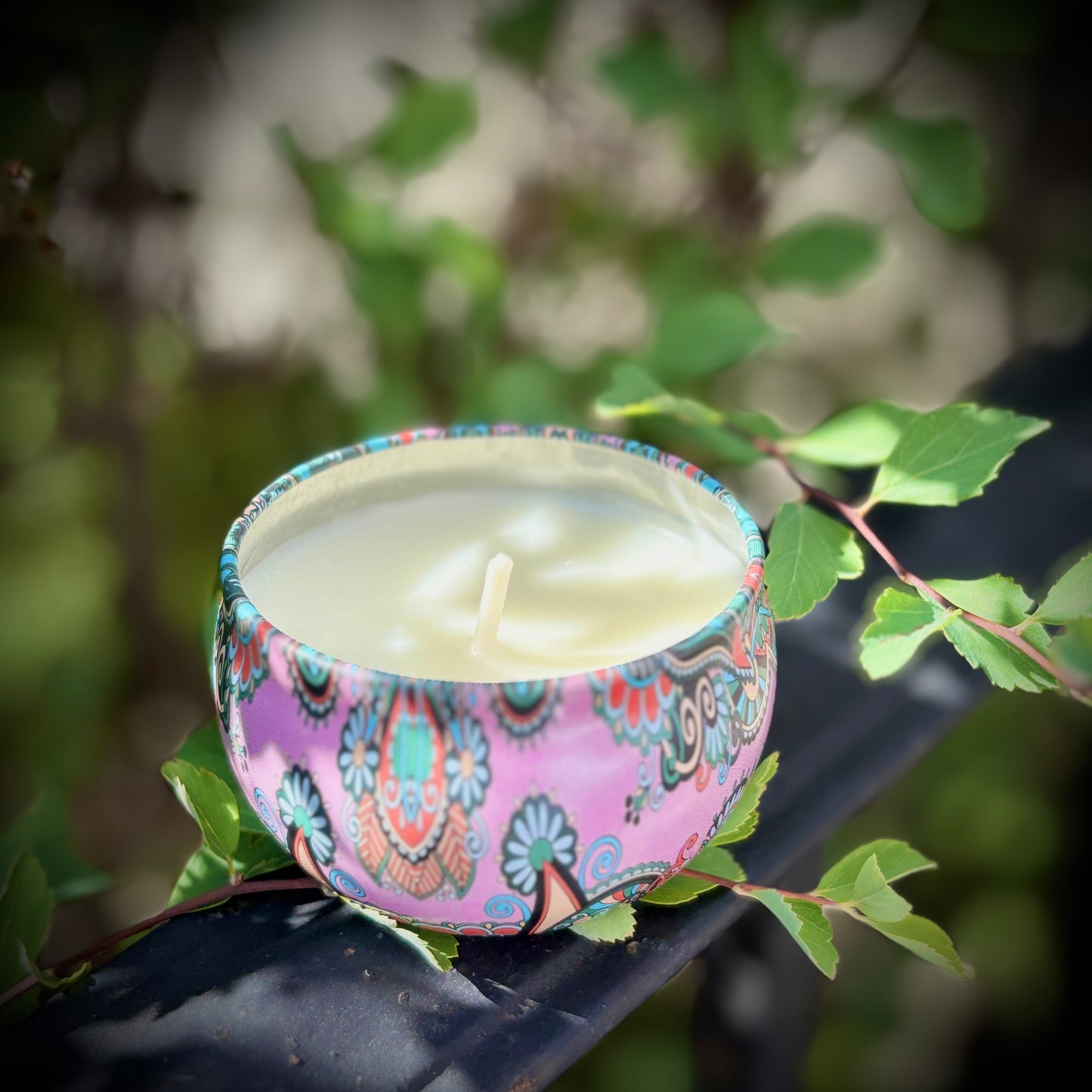 Decorative candle in a colorful holder on a leafy branch