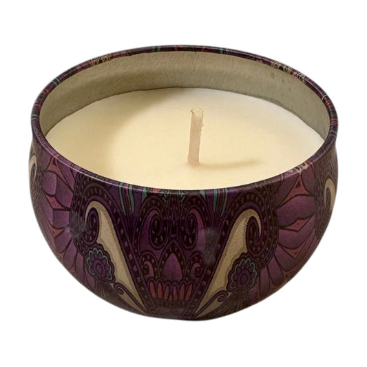 Candle in a decorative purple and beige container on a white background