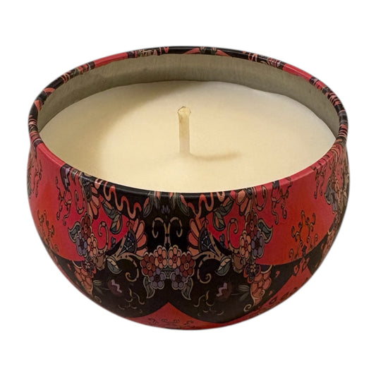 Candle in a decorative red and black container on a white background