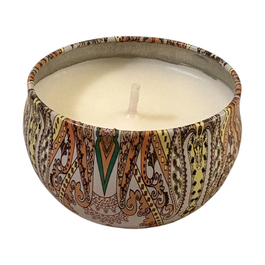 Candle in a decorative tin with intricate patterns on a white background
