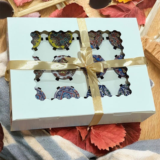 Gift box with decorative items inside, tied with a ribbon, on a wooden surface with autumn leaves.